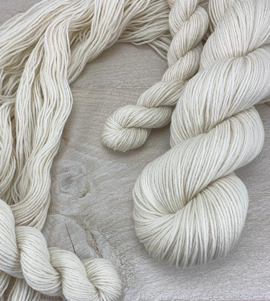 Undyed yarn of 20g mini BFL and 100g skeins of BFL against a grey wood background.